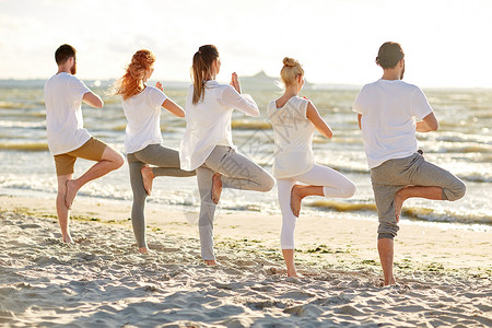 瑜伽,健身,运动健康的生活方式群人海滩上的树姿势图片
