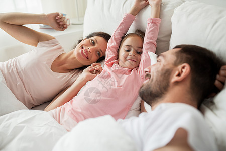人,家庭早晨的快乐的孩子,父母醒来家里的床上图片