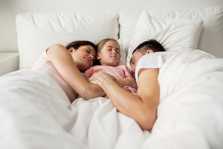 人家庭休息的快乐的孩子,父母睡家里的床上图片