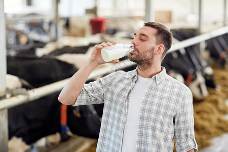 农业农业人民畜牧业快乐的轻人农民奶牛场的牛棚里的瓶子里喝牛奶图片