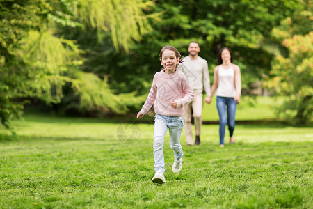 家庭父母收养人的快乐的母亲父亲小女孩夏季公园散步,玩得开心图片
