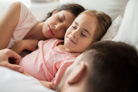 人家庭休息的快乐的孩子,父母睡家里的床上图片