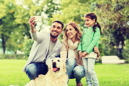 家庭,宠物,动物,技术人的快乐的家庭与拉布拉多猎犬公园用智能手机自拍图片