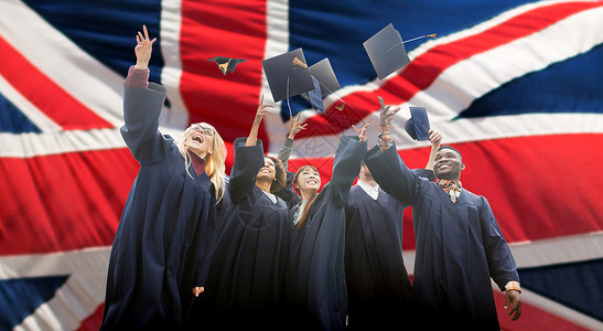 教育,毕业人的群快乐的国际学生穿着学士学位礼服,英国背景下投掷沙板图片