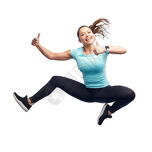 运动,健身,运动人的快乐的微笑轻女子跳空中的白色背景竖大拇指图片