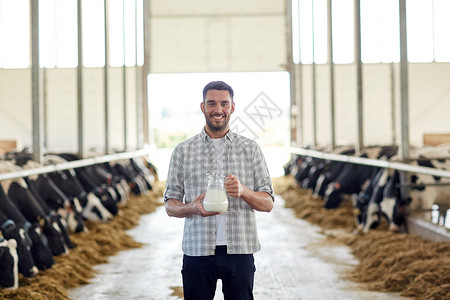 农业,人畜牧业的快乐的轻人农民奶牛场的牛棚里放罐牛奶图片