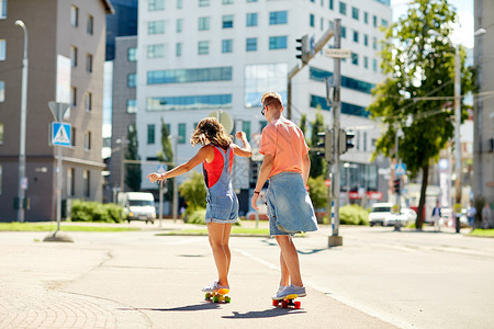 夏天,极限运动人的十几岁的夫妇骑着短的现代巡洋舰滑板城市街道图片