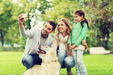 家庭,宠物,动物,技术人的快乐的家庭与拉布拉多猎犬公园用智能手机自拍图片