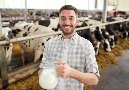 农业农业人畜牧业的快乐的微笑轻人农民,奶牛场的牛棚里放牛奶图片