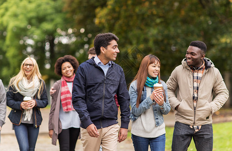 人友谊交流国际理念群快乐的朋友沿着秋天的公园散步,喝咖啡图片