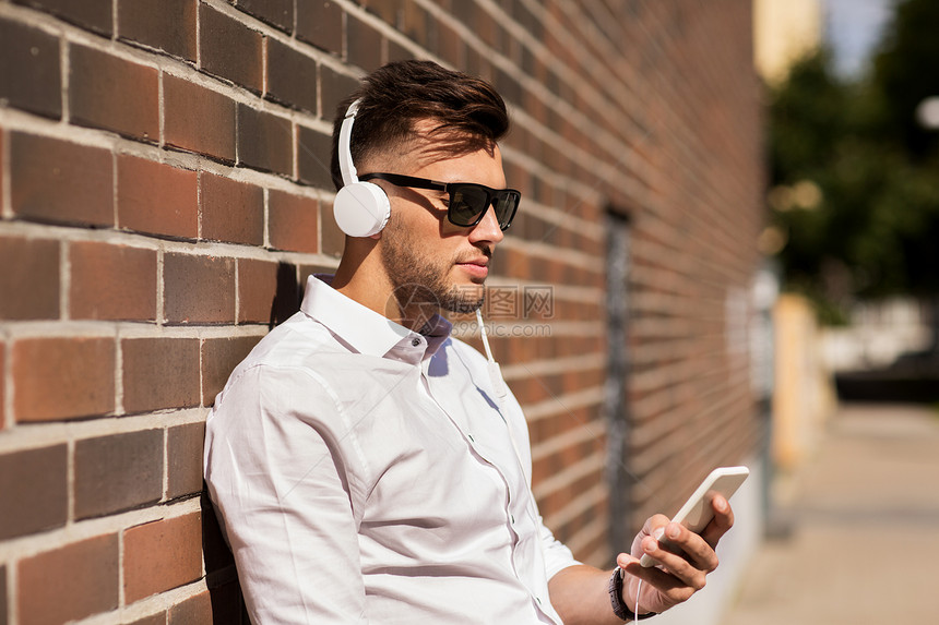 人,技术生活方式快乐的轻人带着耳机智能手机城市听音乐图片