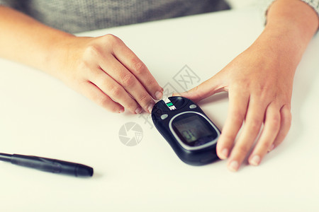 药物,糖尿病,血糖,保健人的用血糖仪密切妇女的手,并家里测试条纹检查血糖水平图片