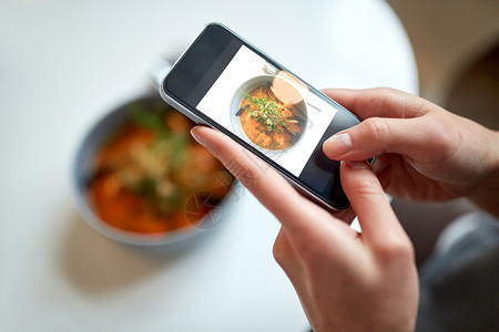 食物,新北欧美食,技术,饮食人的女人与智能手机拍照碗海鲜汤与鱼蓝色贻贝餐厅图片