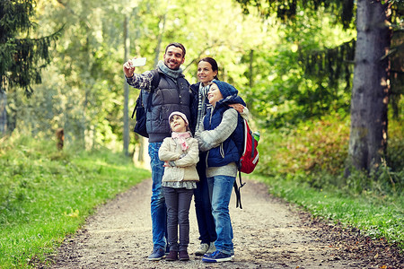 旅行,旅游,徒步旅行,技术人的快乐的家庭与背包采取自拍智能手机树林图片