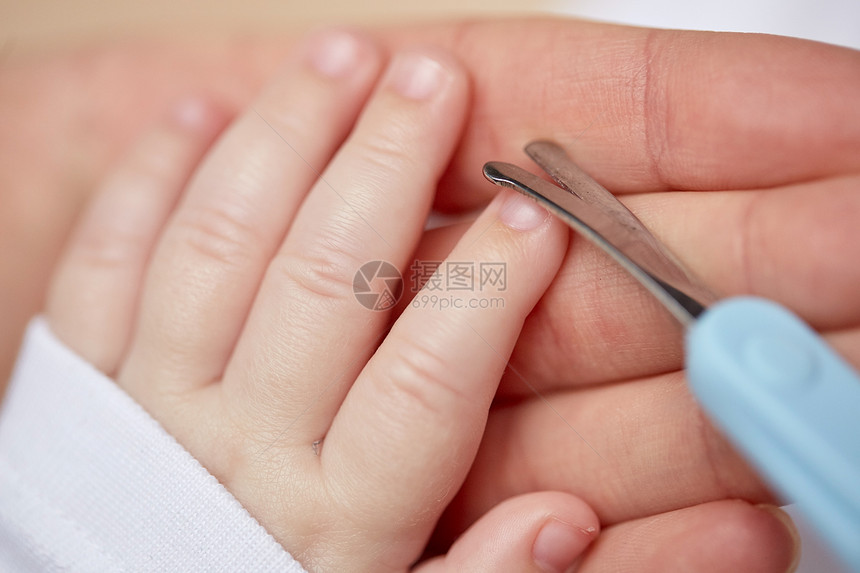 母亲人儿童保育的用剪刀修剪婴儿指甲把母亲的手收来图片