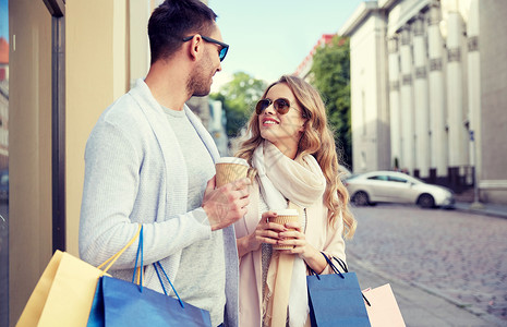 销售,消费主义人们的幸福的夫妇与购物袋咖啡纸杯商店橱窗城市城市里购物袋咖啡的幸福夫妇背景图片