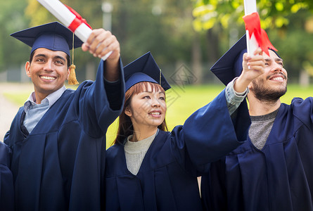 国际证书教育毕业人的群快乐的国际学生穿着灰浆板学士服,毕业证书庆祝成功文凭的迫击炮板上快乐的学生背景