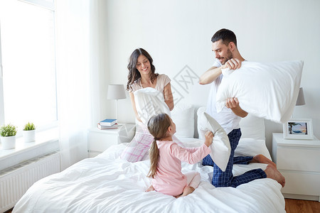 人,家庭早晨的快乐的孩子与父母床上枕头打架家幸福的家庭床上打枕头图片