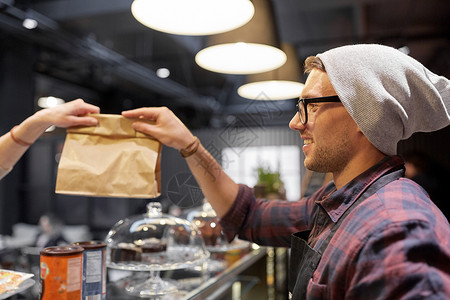小企业,人服务理念男子卖家给顾客纸袋咖啡馆卖人咖啡馆给顾客送纸袋图片
