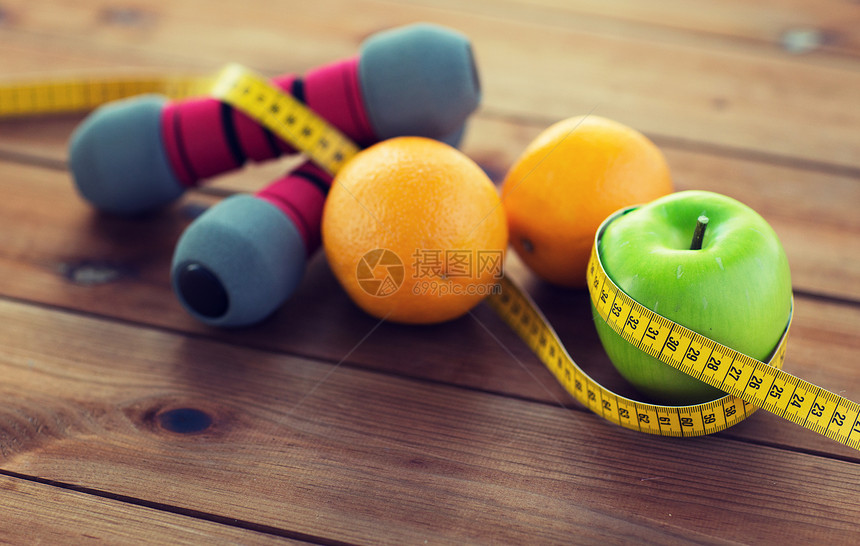 运动,健身,饮食物品的哑铃绿色苹果与橘子包裹测量磁带木桌上哑铃,水果测量磁带图片