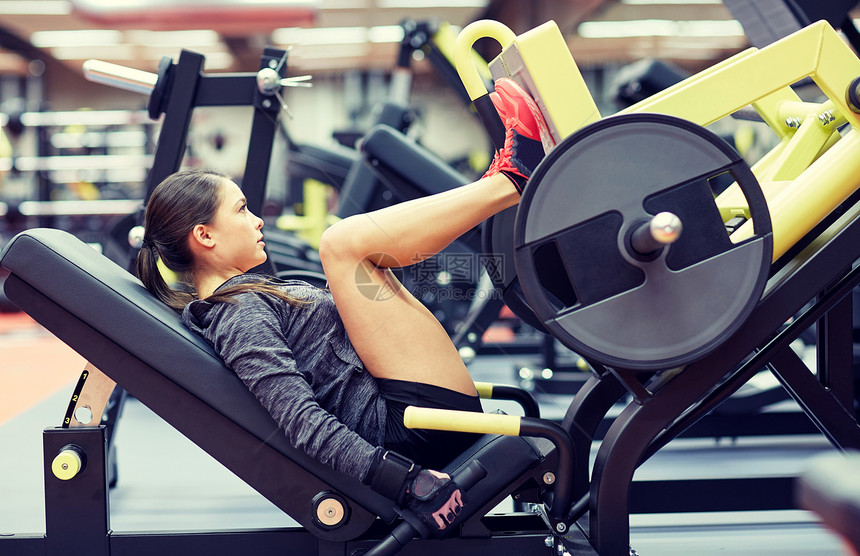 健身,运动,健美,锻炼人的轻妇女健身房的腿部压力机上弯曲肌肉妇女健身房的腿部压力机上弯曲肌肉图片