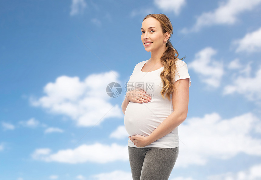 怀孕,母亲,人期望的快乐的孕妇触摸她的大肚子蓝天云彩的背景快乐的孕妇抚摸着她的腹部图片