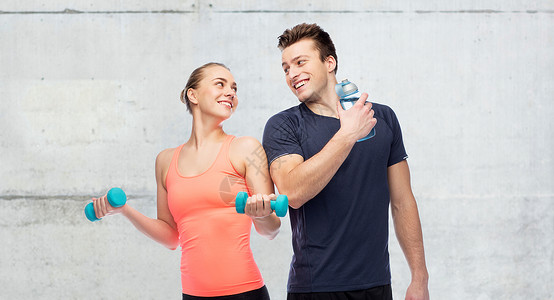 运动,健身人的快乐的运动男女与哑铃水瓶混凝土墙壁背景哑铃水的男男女女图片