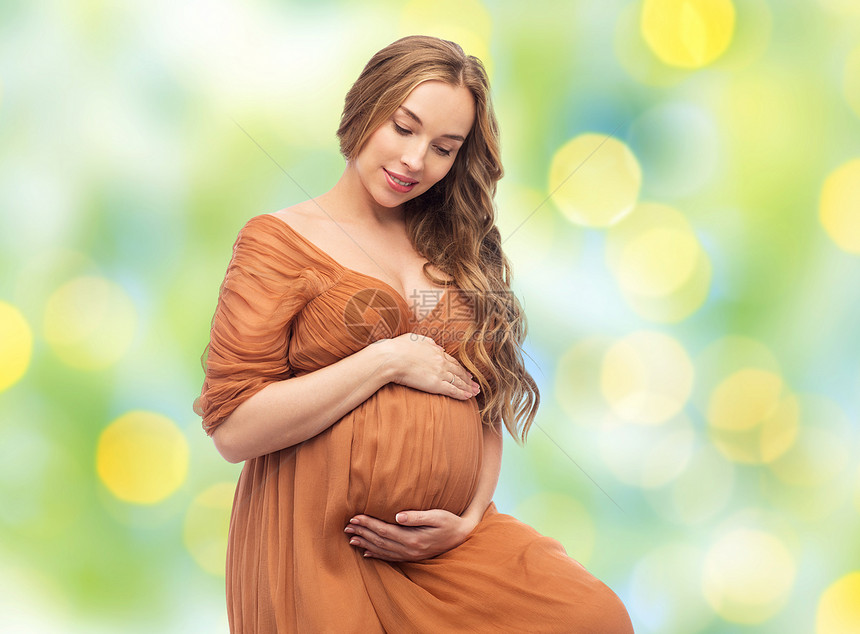 怀孕,母亲,人期望的快乐的孕妇触摸她的大肚子夏天的绿灯背景快乐的孕妇抚摸她的大肚子图片