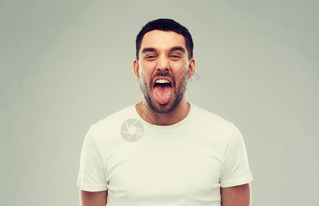 表情,粗鲁人的人他的舌头灰色的背景灰色背景上露出舌头的人图片