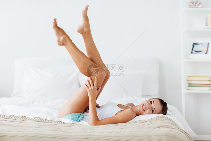 人,美,脱毛,脱毛身体护理的美丽的女人躺床上,触摸光滑的腿部皮肤家庭卧室快乐的女人躺床上,摸着家里的腿图片
