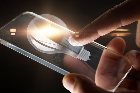 商业,人技术手与智能手机灯泡投影黑色背景手与智能手机灯泡投影图片