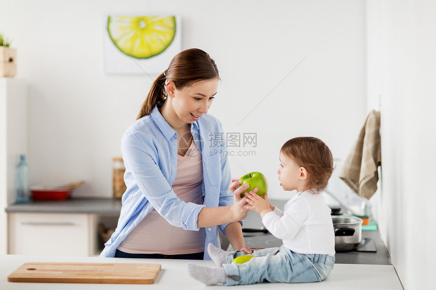 家庭,食物,健康饮食,人母亲的快乐的轻母亲给婴儿家里的厨房妈妈家里的厨房给婴儿送绿苹果图片