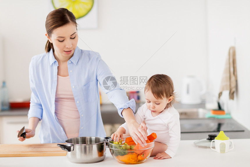 家庭,食物,健康饮食,烹饪人的快乐的母亲小女婴与蔬菜锅家里厨房快乐的母亲婴儿家厨房饭图片