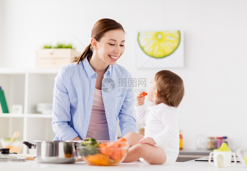 家庭,食物,健康的饮食,烹饪人们的快乐的母亲小宝贝女孩家里的厨房胡萝卜快乐的母亲婴儿家里的厨房吃饭图片