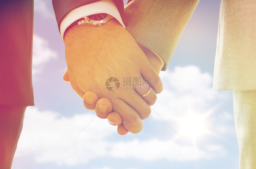 人,同婚姻爱情亲密的快乐男夫妇牵手结婚戒指天空太阳背景把戴着结婚戒指的男手收来图片