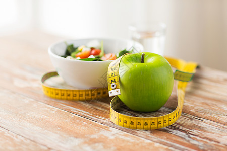 饮食,健康饮食,食物减肥绿苹果测量磁带与沙拉木桌上绿苹果测量磁带图片