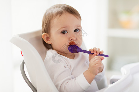 食物,孩子,喂养人的婴儿用勺子坐高椅子上,家吃饭带勺子的婴儿家吃食物图片