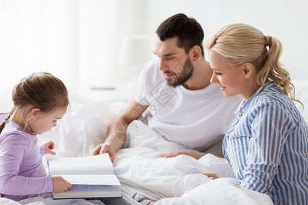 人,家庭早晨的快乐的孩子与父母家里床上看书家床上快乐的家庭读物图片