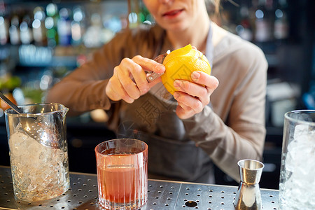 酒精饮料,人豪华女人调酒师与璃剥皮机橘子准备鸡尾酒酒吧酒保酒吧里剥橘子皮鸡尾酒背景图片