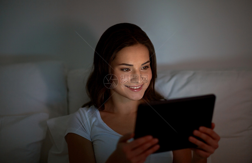 技术,互联网,沟通人的快乐的微笑轻妇女与平板电脑电脑床上家里的卧室晚上轻的女人家里卧室的床上平板电脑图片