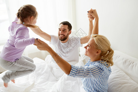 家庭人的快乐的孩子家里父母床上玩幸福的家庭家里的床上玩得开心图片