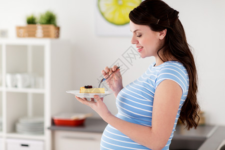怀孕,人垃圾食品的快乐的孕妇家里厨房吃蛋糕快乐的孕妇家里厨房吃蛋糕图片