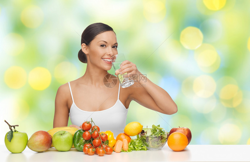 人,饮食,健康饮食食物快乐的女人喝水璃与水果蔬菜绿色的夏季灯光背景下快乐的女人喝杯水健康的食物图片