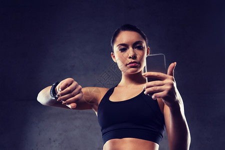 肌肉细胞体育,健身,技术人的轻的女人与心率手表智能手机健身房健身房里心率手表智能手机的女人背景