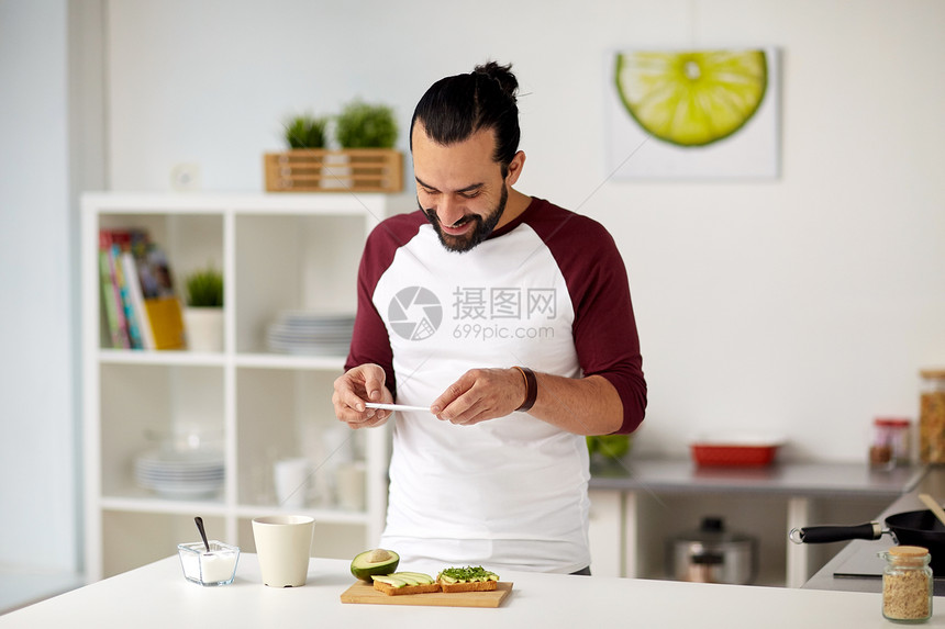 素食,健康饮食,人,技术早餐男人与智能手机拍摄蔬菜三明治家庭厨房男人家用智能手机拍摄食物图片