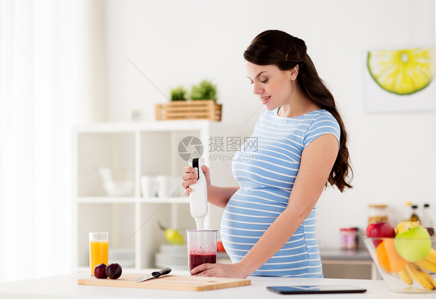 健康的饮食,烹饪,怀孕人的孕妇与搅拌机准备水果冰沙饮料家里厨房孕妇家用搅拌机煮水果图片