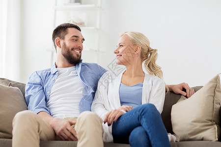 爱,家庭人的微笑的幸福夫妇坐家里的沙发上微笑的幸福夫妇坐家里的沙发上图片