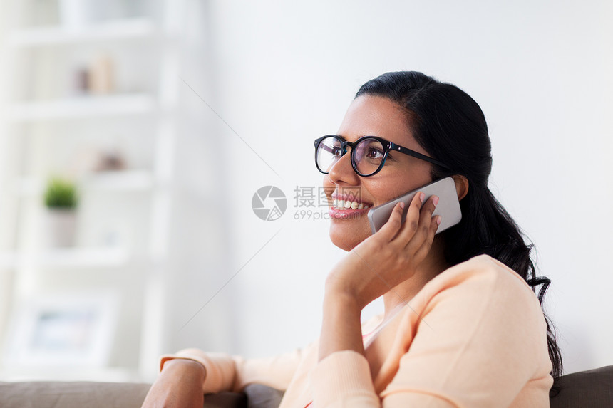 人,技术,沟通休闲快乐的微笑轻印度妇女戴着眼镜,家里打电话给智能手机快乐的印度女人家里打电话给智能手机图片