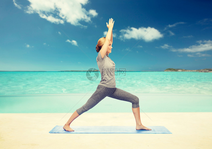 健身,运动,人健康的生活方式妇女瑜伽战士姿势垫子上的海滩背景女人垫子上瑜伽战士的姿势图片