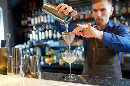 酒精饮料,人奢侈的酒保把鸡尾酒床过滤器倒入酒吧的璃调酒师酒吧准备鸡尾酒背景图片